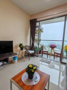 - un salon avec une télévision et une table fleurie dans l'établissement Kensington Sunrise sg, Palas Horizon,kea farm, à Brinchang