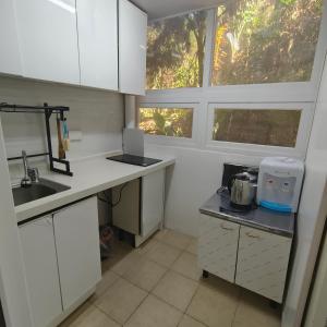 a kitchen with white cabinets and a sink and a window at Cozy Condo near Burnham in Baguio