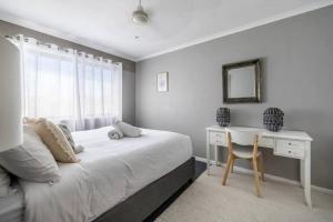 a bedroom with a bed and a desk and a chair at NEW! Breezy, Stylish 3BR Southport Oasis! in Gold Coast