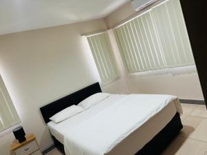 a bedroom with a bed with white sheets and a window at Paradise Apartment Suva in Suva
