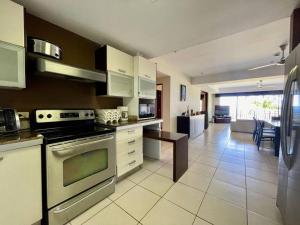 a kitchen with a stove top oven next to a living room at Ocean view apartment at Las Vistas Nativa Resort in Puntarenas
