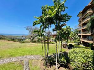 a park with palm trees in front of a building at Ocean view apartment at Las Vistas Nativa Resort in Puntarenas