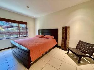 1 dormitorio con 1 cama, 1 silla y 1 ventana en Ocean view apartment at Las Vistas Nativa Resort, en Puntarenas
