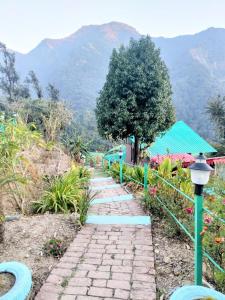 a stone pathway with a tree and mountains in the background at Valley view camps &cottages in Nainital