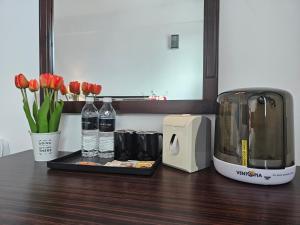 a counter with a toaster and bottles of water and flowers at Go Lodge Hotel Kuantan in Kuantan