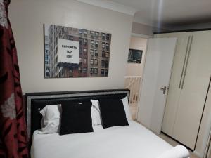 a bedroom with a white bed with black pillows at Orchard house in Greenwich