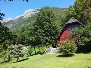 a red cabin in a field with a mountain at Apartma Brin Bovec in Bovec