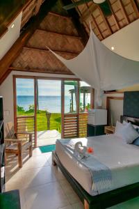 een slaapkamer met een bed en uitzicht op de oceaan bij Mango Bay Resort in Namatakula