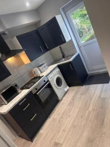 a kitchen with black cabinets and a white appliance at Paradise Vuze in Tilehurst