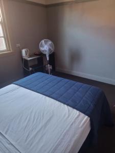 a bedroom with a bed with a blue blanket and a fan at Coffs Harbour Hotel in Coffs Harbour