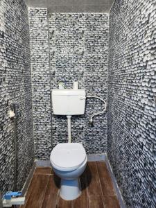 La salle de bains est pourvue de toilettes blanches et d'un mur en carrelage. dans l'établissement Dk's Paradise Homestay, à Agra