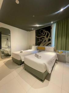 two beds in a hotel room with a mirror at SocialTel Koh Samui in Chaweng