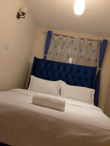 a large bed with a blue headboard and white pillows at Sweet Homes Ngong Road in Nairobi