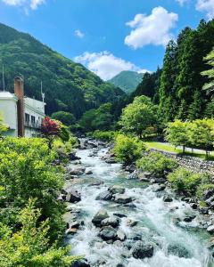un río con rocas, árboles y montañas en MONJUNO FUKUCHI, en Kamikishida