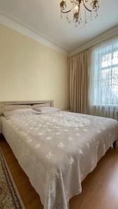 1 dormitorio con cama blanca y ventana en Salamat Apartments - Best location 8, en Bishkek