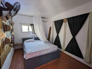 a bedroom with a bed with a mosquito net at La Maison Blanche in Ndangane