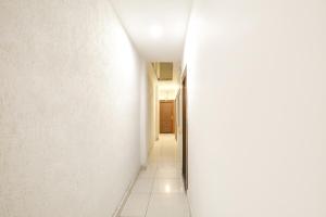a hallway with white walls and a white tile floor at FabHotel Madhuban Inn in Rishīkesh