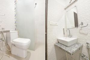 a white bathroom with a toilet and a sink at FabHotel Madhuban Inn in Rishīkesh