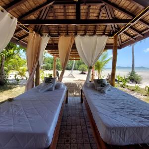 two beds in a pavilion with the beach in the background at La Tranquilidad Beach Club 