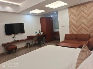 Habitación con cama, escritorio y TV. en HOTEL KADAMB TREE, en Jabalpur