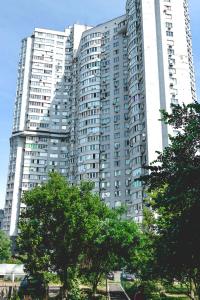 duży budynek apartamentowy z drzewami przed nim w obiekcie Apartment on Hryshka Street w Kijowie
