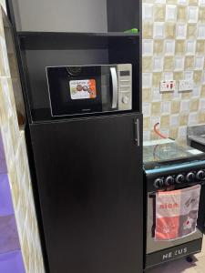 a black refrigerator with a microwave in a kitchen at Belphus Apartments in Lagos