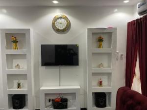 ein Wohnzimmer mit einem TV und einer Uhr an der Wand in der Unterkunft Belphus Apartments in Lagos