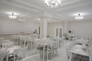 un comedor con mesas blancas y sillas blancas en Status Hotel, en Qarshi