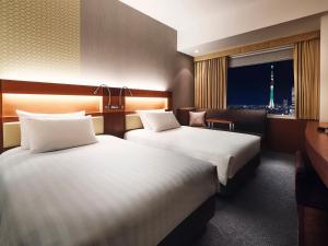 two beds in a hotel room with a view of the eiffel tower at Lotte City Hotel Kinshicho in Tokyo