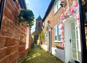 an alley between two brick buildings with flowers at Tarporley Holiday Cottage in Tarporley