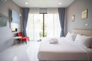 - une chambre avec un grand lit blanc et une chaise rouge dans l'établissement SeeView Resort (ซีวิว รีสอร์ต), à Ban Pak Nam