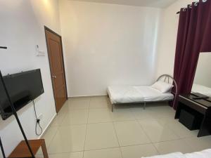 a small room with a bed and a television at KSP Guest House in Melaka