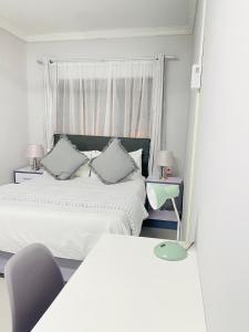 a white bedroom with two beds and a window at Pelican Apartment in Durban