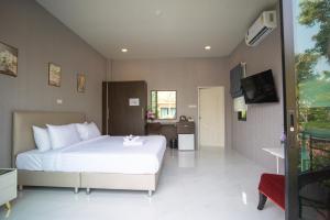um quarto com uma grande cama branca e uma televisão em SeeView Resort (ซีวิว รีสอร์ต) em Ban Pak Nam