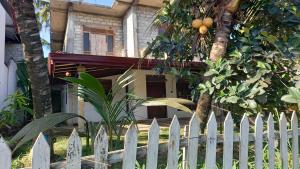 a white picket fence in front of a house at Family Villa Thalpavila in Ambatenna