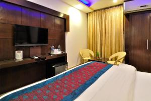 a hotel room with a bed and a flat screen tv at Hotel Shelton in New Delhi