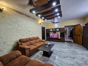uma sala de estar com um sofá e uma mesa em Fully Airconditioned Uber Luxurious Holiday Home. em Kundapur