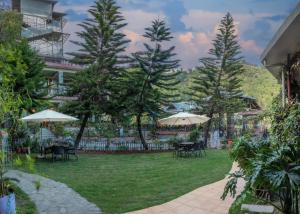 un jardin avec des tables et des parasols en face d'un bâtiment dans l'établissement Starlit Getaway, à Dharamshala