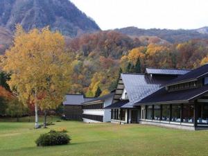 a building with trees and mountains in the background at Towada Prince Hotel in Kosaka