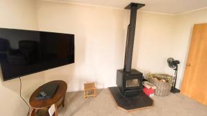 a living room with a stove and a flat screen tv at Pohara's Kauri Lodge in Pohara