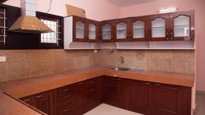 a kitchen with wooden cabinets and a sink at Sai Residency ECR in Chennai