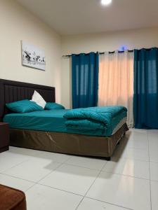 a bedroom with a bed with blue sheets and blue curtains at Fully Furnished Studio Appartment next to Sharaf DG metro Station in Dubai