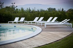 a row of white lounge chairs next to a pool at Agriturismo Ai Casoni in Codognè