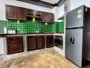 a kitchen with brown cabinets and green tiles at Ocean Front Apartments in Ko Tao