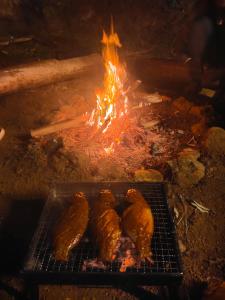 una parrilla con cuatro alimentos con fuego en PAPATHI KUDIL en Kodaikānāl