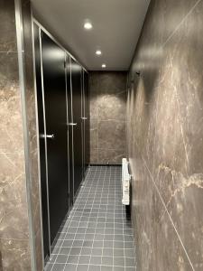 a bathroom with black stalls and a tiled floor at Den Röda Båten in Stockholm