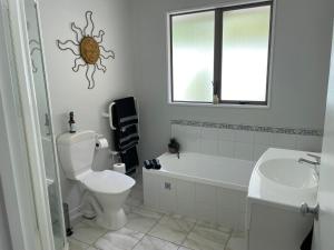 y baño con aseo, bañera y lavamanos. en Villa55, en Christchurch