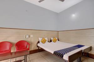 a small room with a bed and two red chairs at SPOT ON Ganga Yatri Nivas in Gundlupet