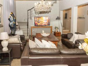 a living room with leather furniture and a chandelier at Muckleneuk Manor in Pretoria