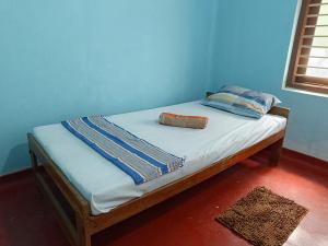 een bed in een kamer met een blauwe muur bij Vijay Thulasi Beach View in Nilaveli